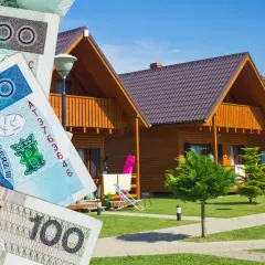 Polskie banknoty na tle drewnianych domków letniskowych.