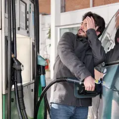 Mężczyzna zrezygnowany podczas tankowania samochodu. Ceny paliwa przyprawiają o ból głowy.