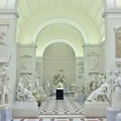 Interno della Galleria dell'Accademia con sculture classiche in marmo bianco, pavimentazione a scacchi e soffitto a volta.