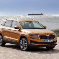 Pomarańczowa Skoda Karoq na tle morza. Sprawdź aktualny skoda cennik i wybierz swój wymarzony model.