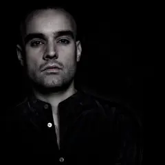Ritratto intenso di un dj spagnolo famoso, con sguardo penetrante e labbra colorate.