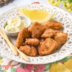 Deliciosas lagrimitas de pollo crujientes, servidas con mayonesa y limón en un plato blanco.