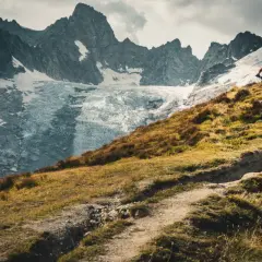 Rowerzysta na szlaku podczas Tour du Mont Blanc, z lodowcem i skalistymi szczytami w tle.