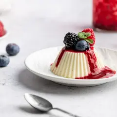 Vegane Panna Cotta mit Beerensoße und frischen Beeren, ein leichter Genuss.