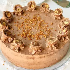 Eine köstliche Rocher Torte mit Schokoladencreme und gehackten Nüssen, dekoriert mit halbierten Rocher Kugeln.