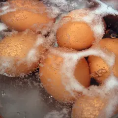Des œufs bruns bouillent dans une casserole d'eau froide. Le temps de cuisson d'un œuf dur est crucial pour une texture parfaite.