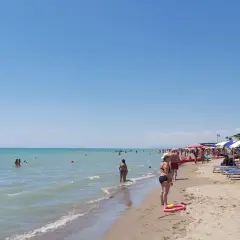 Giornata di sole al Metaponto Lido. Gente in acqua e sotto gli ombrelloni, bagnanti che si godono la spiaggia.