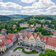Urokliwy rynek w Dusznikach Zdroju z kolorowymi kamieniczkami i zielenią.
