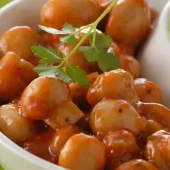 Champignons à la grecque, petits et tendres, nappés d'une sauce savoureuse et garni d'une feuille de persil.