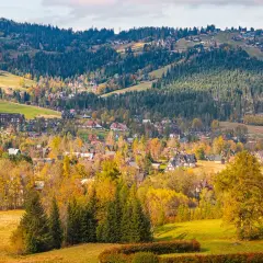 Widok na Zakopane jesienią, z górami i lasami w tle.