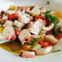 Ein köstlicher **pulpo salat original** mit zarten Oktopus-Stücken, Tomaten und frischen Kräutern in Olivenöl.
