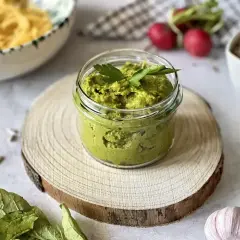Słoiczek domowego pesto z bazylii, gotowy do podania z makaronem. Obok czosnek i słonecznik.