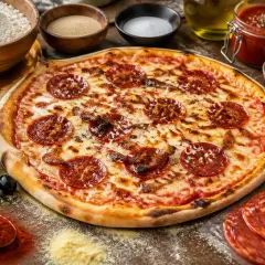 Pizza chorizo appétissante, garnie de rondelles de chorizo croustillantes, entourée d'ingrédients frais pour une création parfaite.