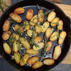 Goldbraune rosmarin kartoffeln mit Knoblauch und Kräutern in einer Gusseisenpfanne, bereit zum Servieren.