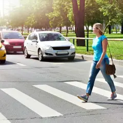 Kobieta przechodzi przez pasy, a samochody stoją. Pamiętaj, co grozi za potrącenie pieszego na pasach.