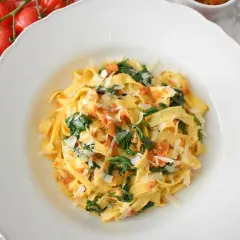 Pyszne tagliatelle ze szpinakiem i pomidorami, posypane parmezanem. Idealne danie na szybki obiad.