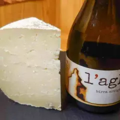 Un pezzo di formaggio stagionato accanto a una bottiglia di birra artigianale. Un abbinamento perfetto di birra e formaggio.