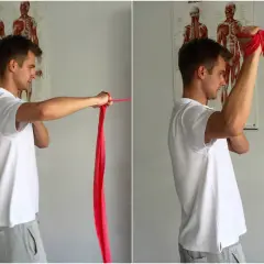 Ćwiczenia z taśmą do budowy stawu ramiennego. Mężczyzna wykonuje ruchy ramieniem z czerwoną taśmą.