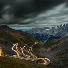 Ślady świateł samochodów wiją się serpentynami na stromych zboczach górskich, tworząc świetlisty szlak na przełęczy Stelvio.