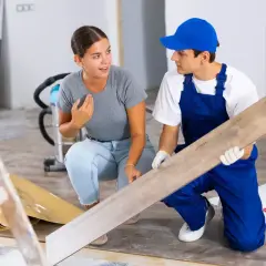 Un artisan montre une lame de parquet à une cliente. Elle s'interroge sur quels travaux peut on déduire des impôts pour ce type de rénovation.