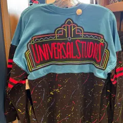 Turkusowy longsleeve z neonowym napisem "Universal Studios" i kolorowymi plamkami na czarnym tle. Idealny na wycieczkę do parku rozrywki!