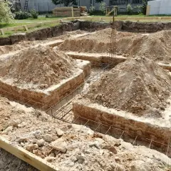 Wykop pod fundamenty bez szalunku, z widoczną zbrojeniem i usypaną ziemią.