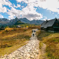 Kamienna ścieżka prowadzi do górskich chat. W oddali majestatyczne Tatry. To piękne zakopane atrakcje.