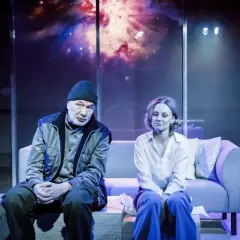 Para siedzi na kanapie w teatrze współczesnym na Mokotowie w Warszawie. Tło sceny to kosmiczna mgławica.