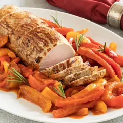 Un arrosto di maiale affettato, servito con peperoni e carote in salsa, un piatto di secondi di carne sfiziosi al forno.