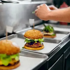 Trois hamburgers appétissants sur des plateaux, prêts pour la livraison. Une image parfaite pour une lettre de motivation restauration rapide.