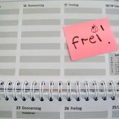 Ein rosa Zettel mit "frei!" und einem lachenden Smiley auf einem Kalenderblatt. Der Zettel könnte für den Freizeitausgleich nach Krankheit stehen.