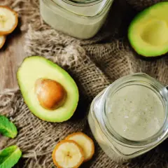 Grön smoothie med avokado och banan, perfekt mat med lite kalorier. Serveras i glasburkar med myntablad på en säckväv.