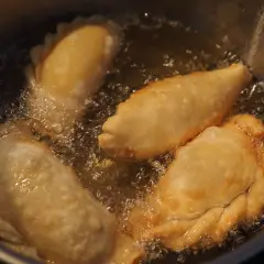 Empanadas de queso dorándose en aceite burbujeante. El aroma tentador llena la cocina.