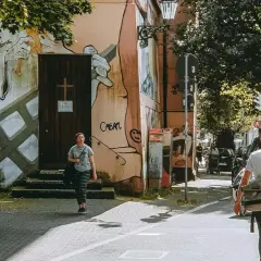Ein Mann geht mit Hund durch eine Straße in Wuppertal, vorbei an einer Wand mit Graffiti.