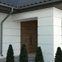 Nowoczesna elewacja z białymi boniami, drewnianymi drzwiami i ozdobnymi elementami.