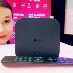 Kobieta prezentuje dekoder i pilot do telewizji T-Mobile Magenta Dom.