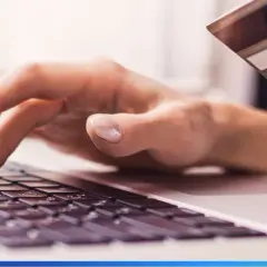 Dłonie wpisujące dane karty płatniczej na klawiaturze laptopa, ilustrujące najpopularniejsze metody płatności online.
