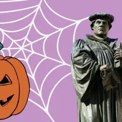 Reformationstag statt Halloween: Martin Luther Statue neben Kürbis und Spinnennetz.