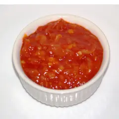 Pomarańczowy, pikantny sos piri piri w białej miseczce, gotowy do podania.