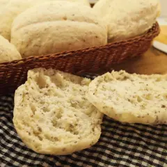 Puszyste bułki bezglutenowe, idealne na śniadanie, leżą w koszyku i na czarno-białej kratce.