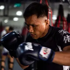 A boxer, sweat beading on his brow, trains intensely. This image shows why is boxing so tiring: constant movement, powerful strikes, and unwavering focus.