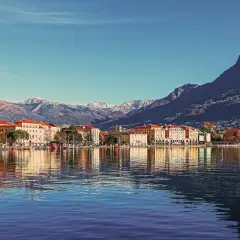 Widok na miasto nad jeziorem w Szwajcarii, z górami w tle. Piękne budynki i odbicia w wodzie. Ceny w Szwajcarii mogą być wysokie, ale widoki są bezcenne.