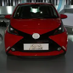 Czerwony samochód z czarnymi akcentami, prezentowany na scenie, z logo "Koło Fortuny" na masce.