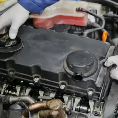 Mechanik w białych rękawiczkach sprawdza silnik, dokręcając śruby pokrywy zaworów. Może to być związane z konserwacją odmy turbiny.