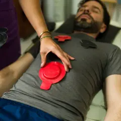 Un homme reçoit un traitement de magnétothérapie pour soulager son arthrose. Des électrodes rouges et noires sont placées sur son torse.