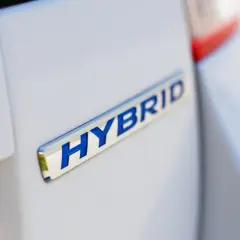 Niebieski napis HYBRID na białym samochodzie.