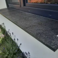Granitowy parapet zewnętrzny, idealny do montażu po ociepleniu ścian. Obok kwitnąca lawenda.