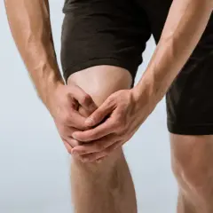 Mężczyzna trzyma się za bolące kolano, co może sugerować gonartrozę kolana. Co to jest?
