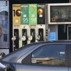 Persona repostando gasolina 95 o 98. El surtidor muestra los precios de los combustibles.