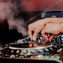 Mani esperte del dj sax mixano la musica, creando un'atmosfera vibrante con fumo e luci soffuse.